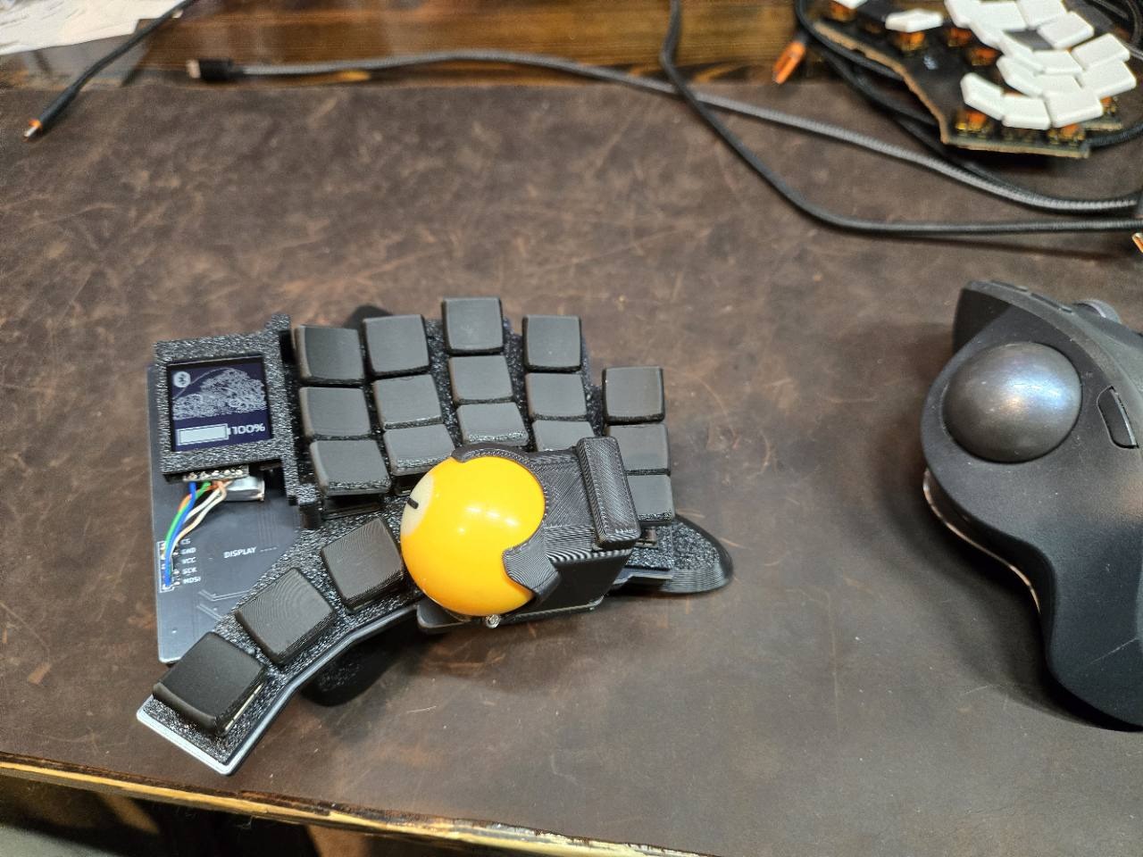 Yellow-trackball prototype on my desk beside a separate trackball mouse.