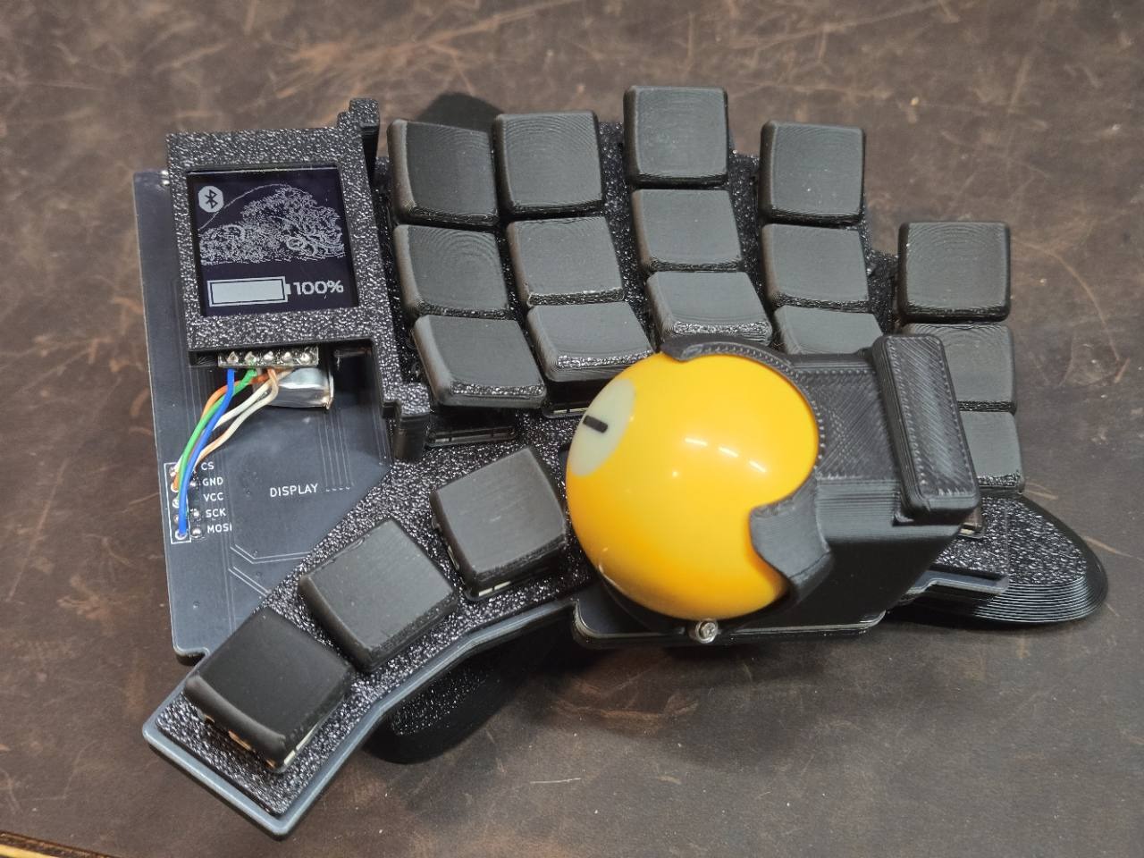 Tempest Dux prototype with black keys, a yellow trackball in a printed mount, and exposed display wiring.